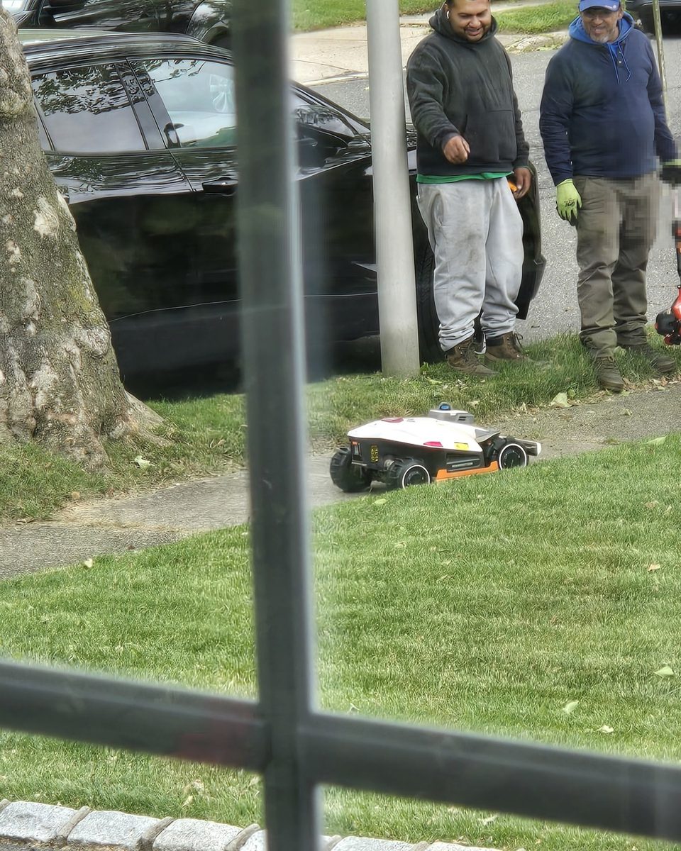 Two landscapers with a string trimmer watching the Luba 3 AWD mow